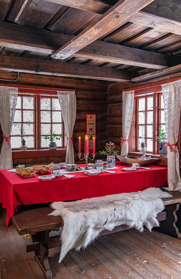 Rustikales Esszimmer mit Holzbalkendecke und rot gedecktem Tisch