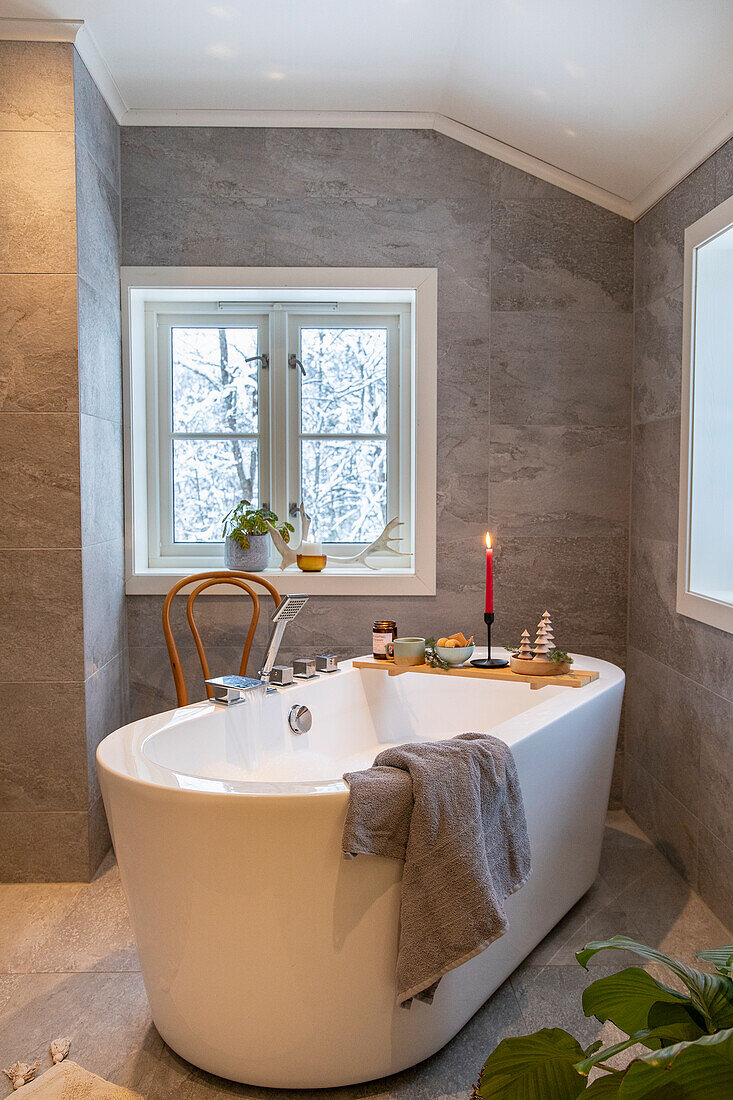 Modern bathroom with freestanding bathtub and Christmas decorations on a wooden shelf