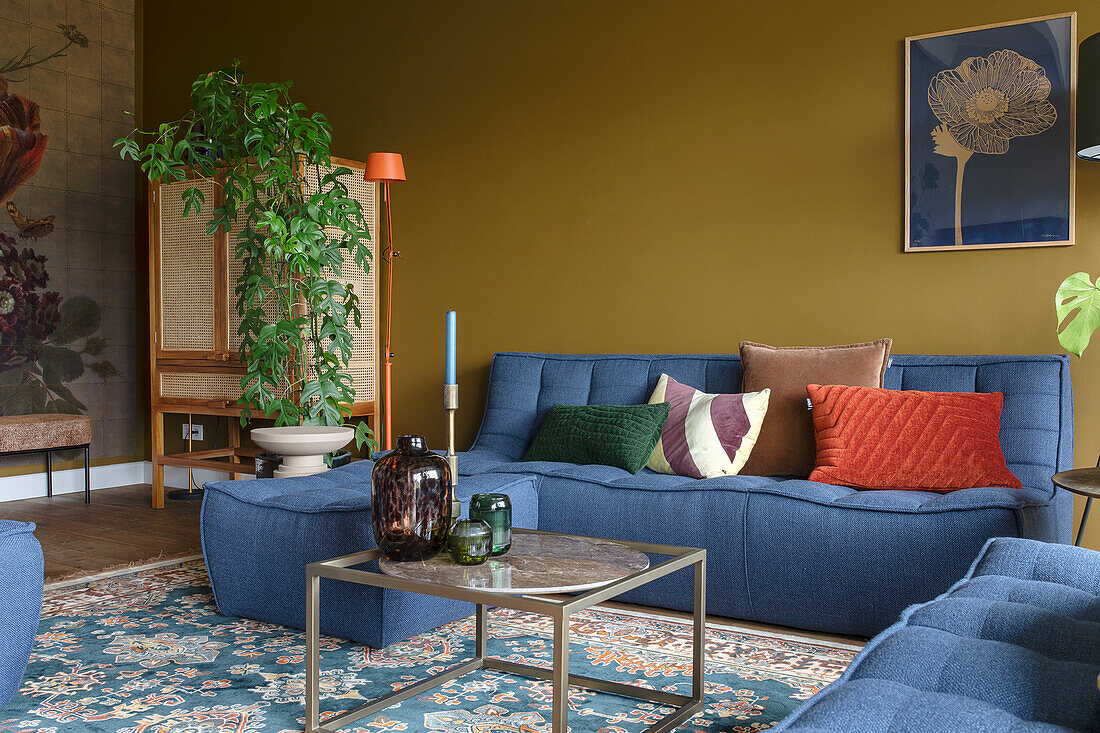 Living room with blue upholstered furniture and ochre-colored wall