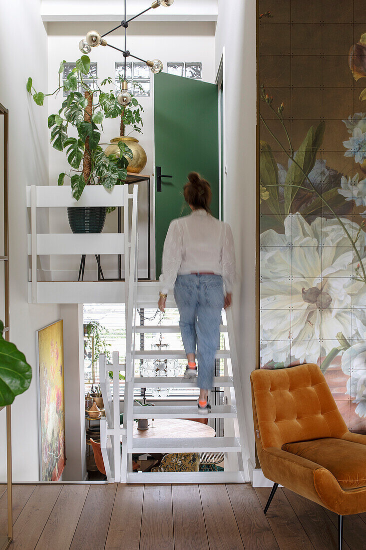 Offenes Treppenhaus führt zu grüner Tür mit großflächiger Blumenwandgestaltung