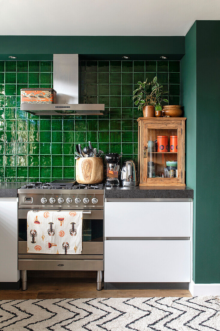 Modern kitchen with green tiled backsplash and stainless steel oven