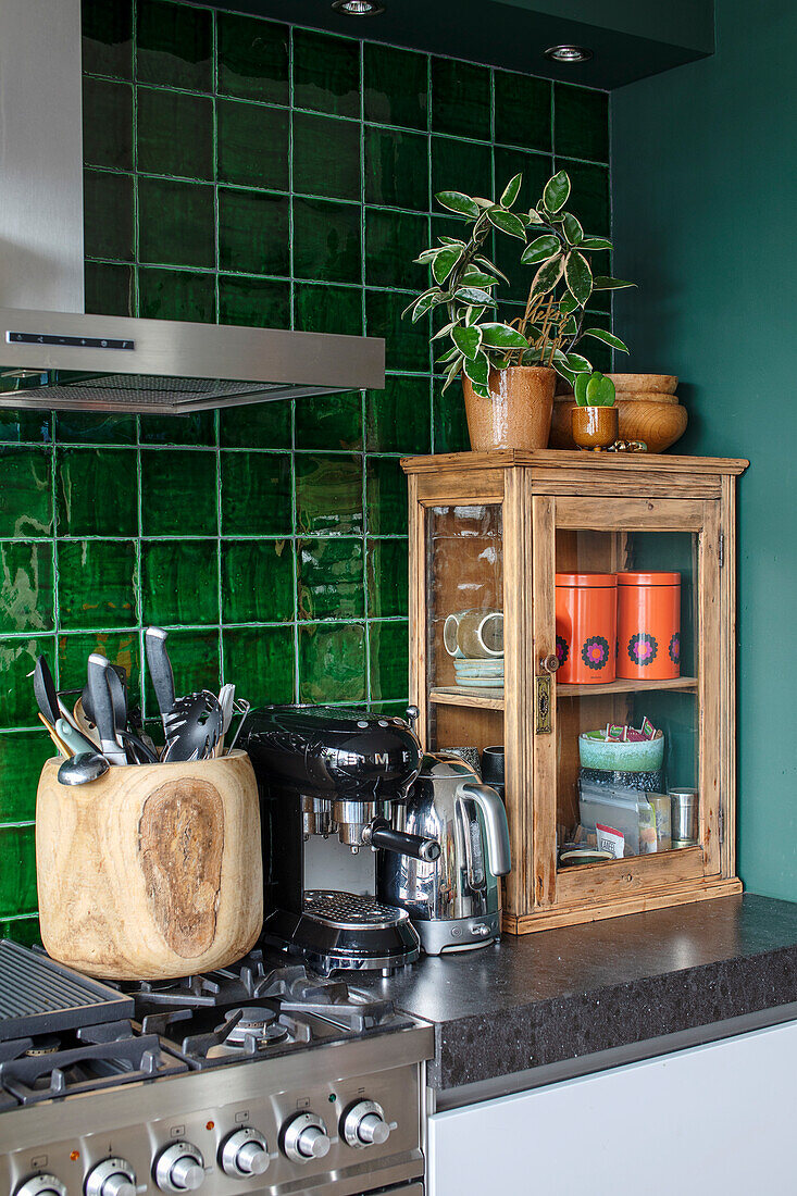 Green kitchen wall with ceramic tiles, kitchen utensils and display cabinet