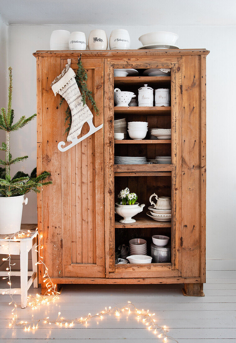 Rustic wooden cupboard with crockery and Christmas stocking