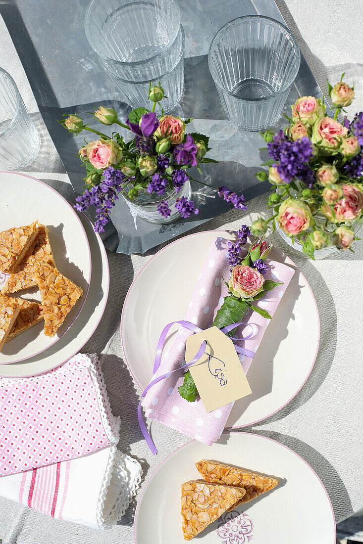 Frühlingshafte Tischdekoration mit Blumensträußchen und Mandelschnitten