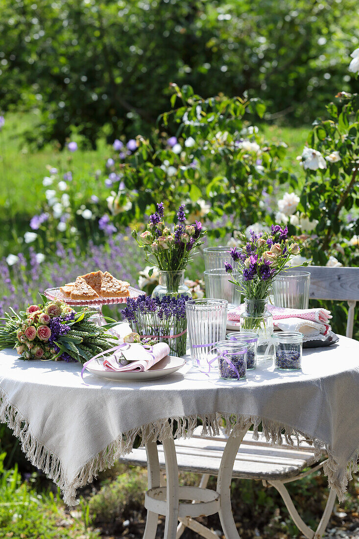 Gedeckter Gartentisch mit Lavendelsträußen und Porzellangeschirr im Sommergarten