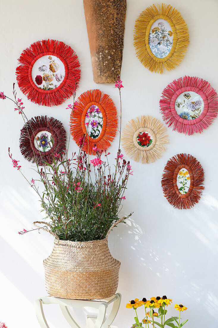 Runde, bunte Fotorahmen mit Blumendekoration vor weißer Wand