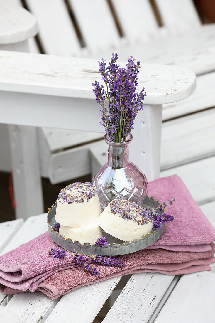 Lavender flowers in a glass vase and lavender soaps on pink towels