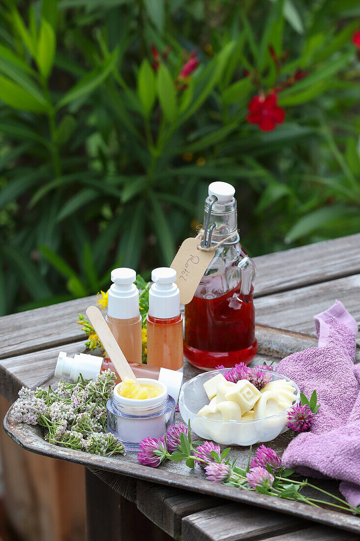 Dekorative DIY-Naturkosmetik mit Blüten auf Holztisch im Garten