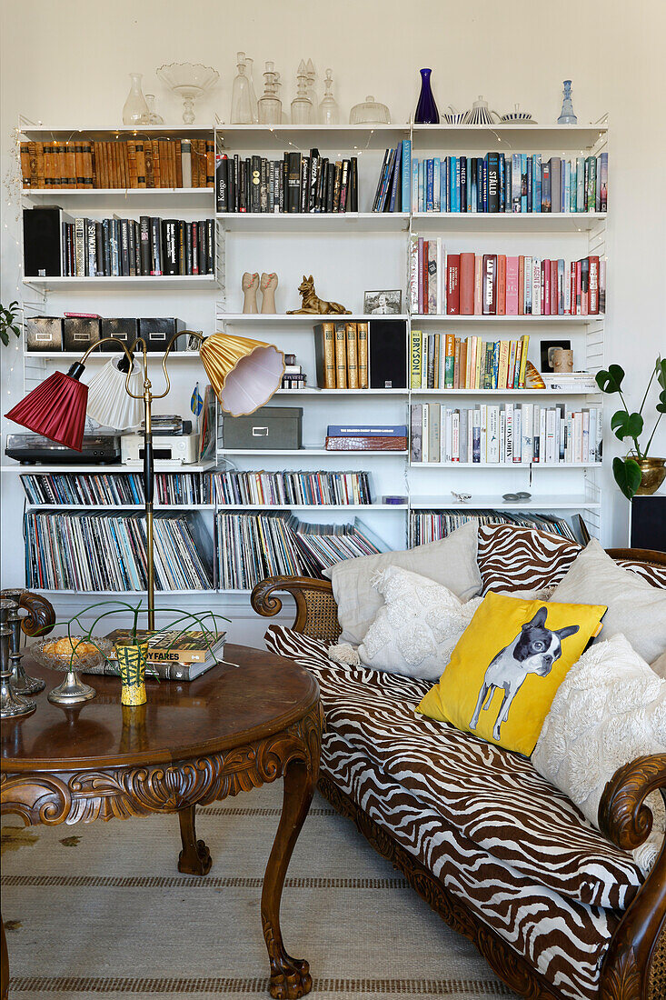 Gemütliche Leseecke mit antikem Tisch und Zebra-Print-Sofa vor Regalwand voller Bücher