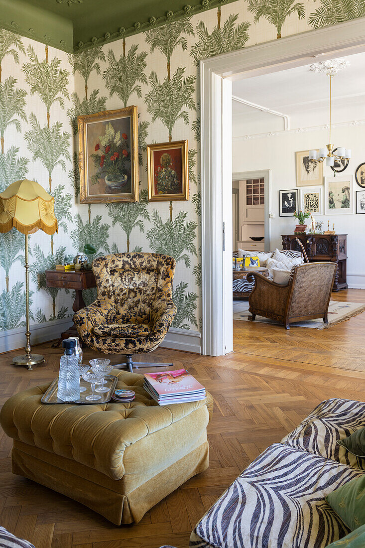 Living room with palm wallpaper, retro lamp and patterned armchairs