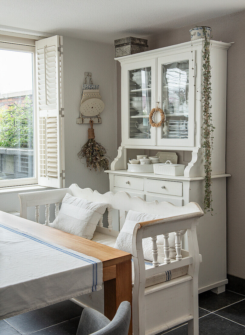 Dining room with white country-style buffet, wooden bench and table with blue and white linen runner