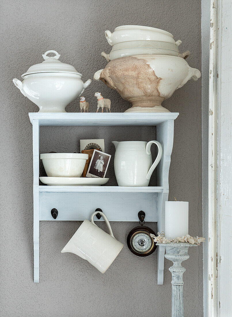 White ceramic crockery and decorations on wall shelf