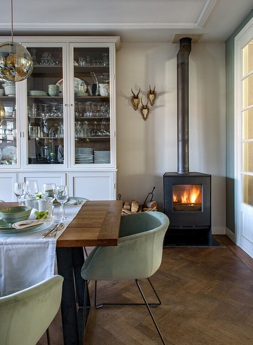 Wood-burning stove in the dining room with glass cabinet and table setting