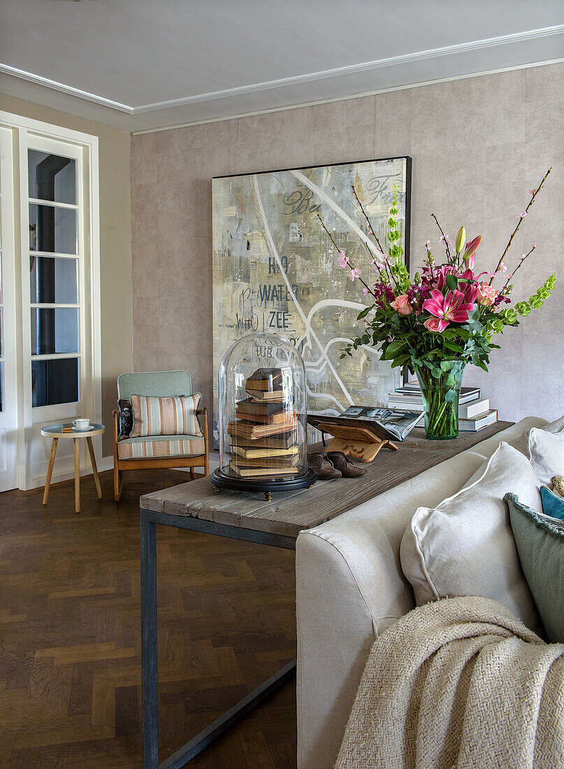 Living room with bouquet of flowers on modern side table and large painting on the wall