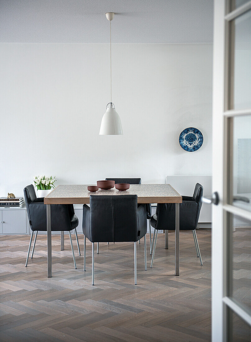 Dining room with black leather chairs and white hanging lamp