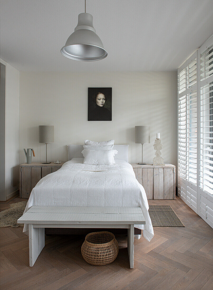 Bedroom with single bed, wooden chest of drawers and louvre windows