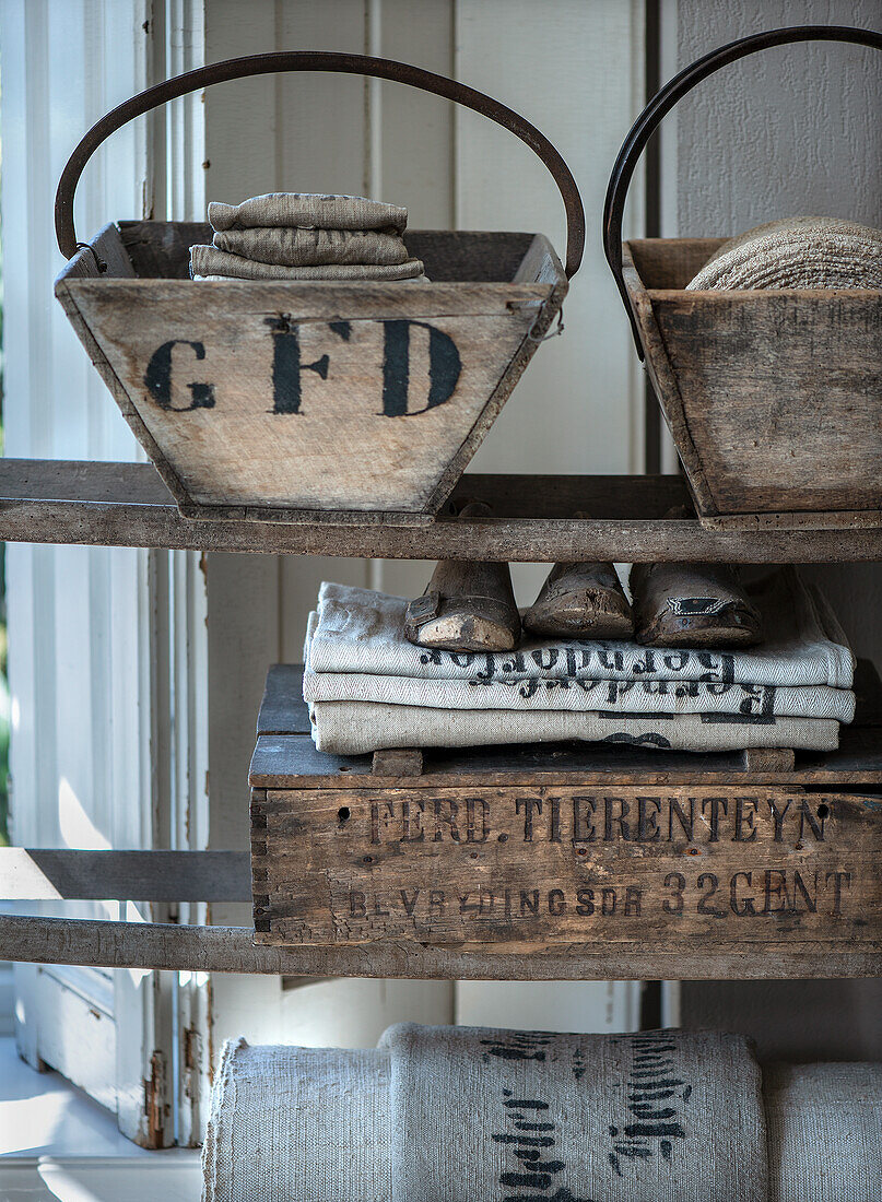 Shelf with vintage wooden boxes, shoe rails and fabric rolls