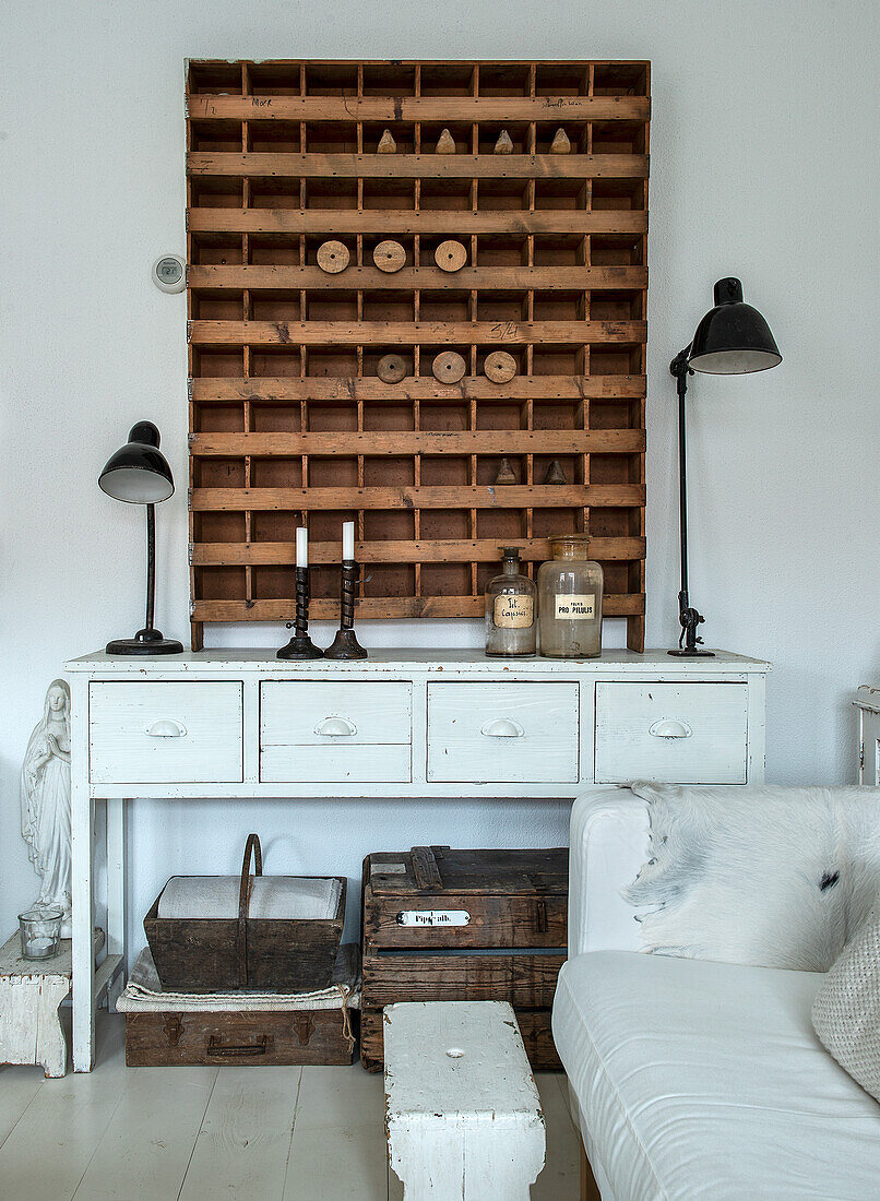 White-painted chest of drawers with drawers, wooden shelf and retro lamps in the living room