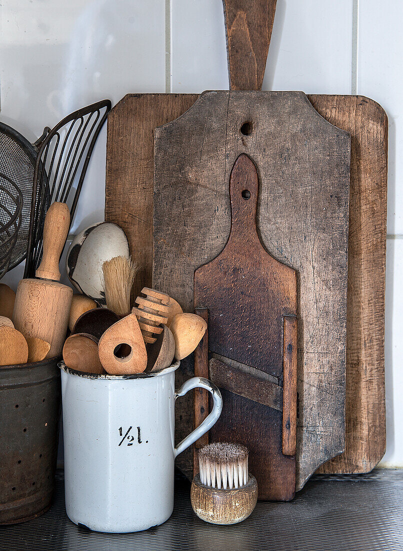 Rustikale Holzbretter und Küchenutensilien in Vintage-Metallbechern