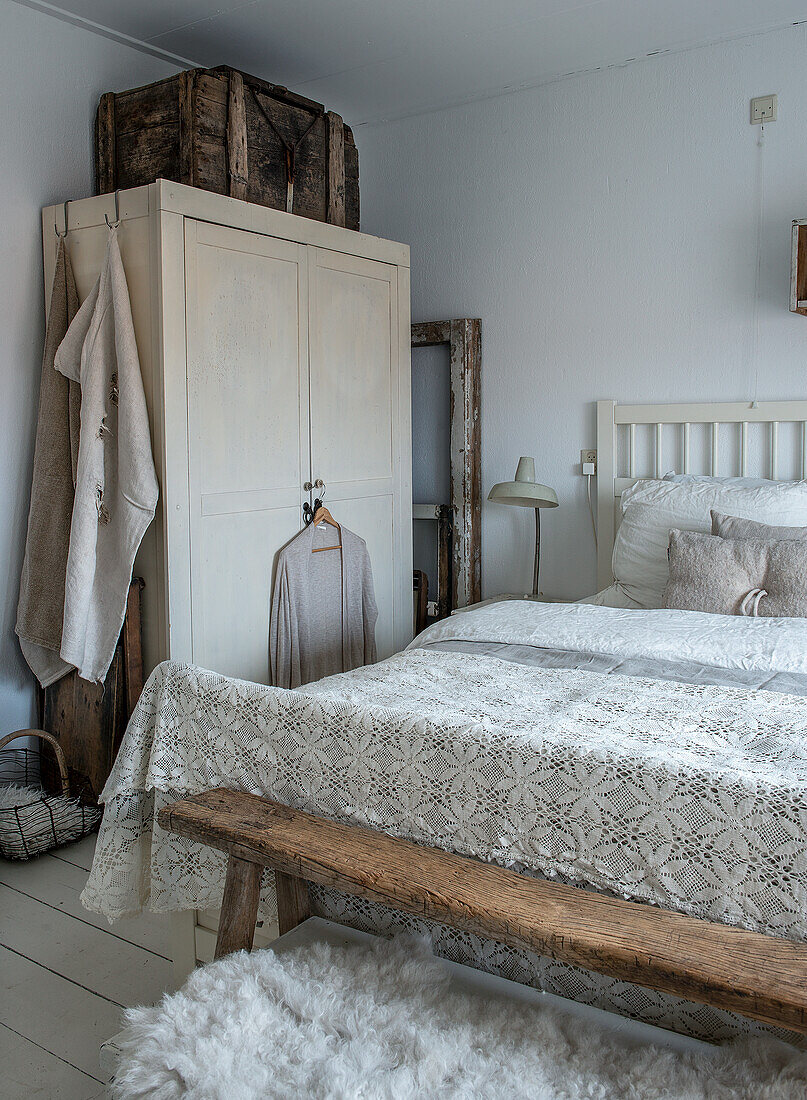 Schlafzimmer im Landhausstil mit weißen Möbeln und Spitzendecke