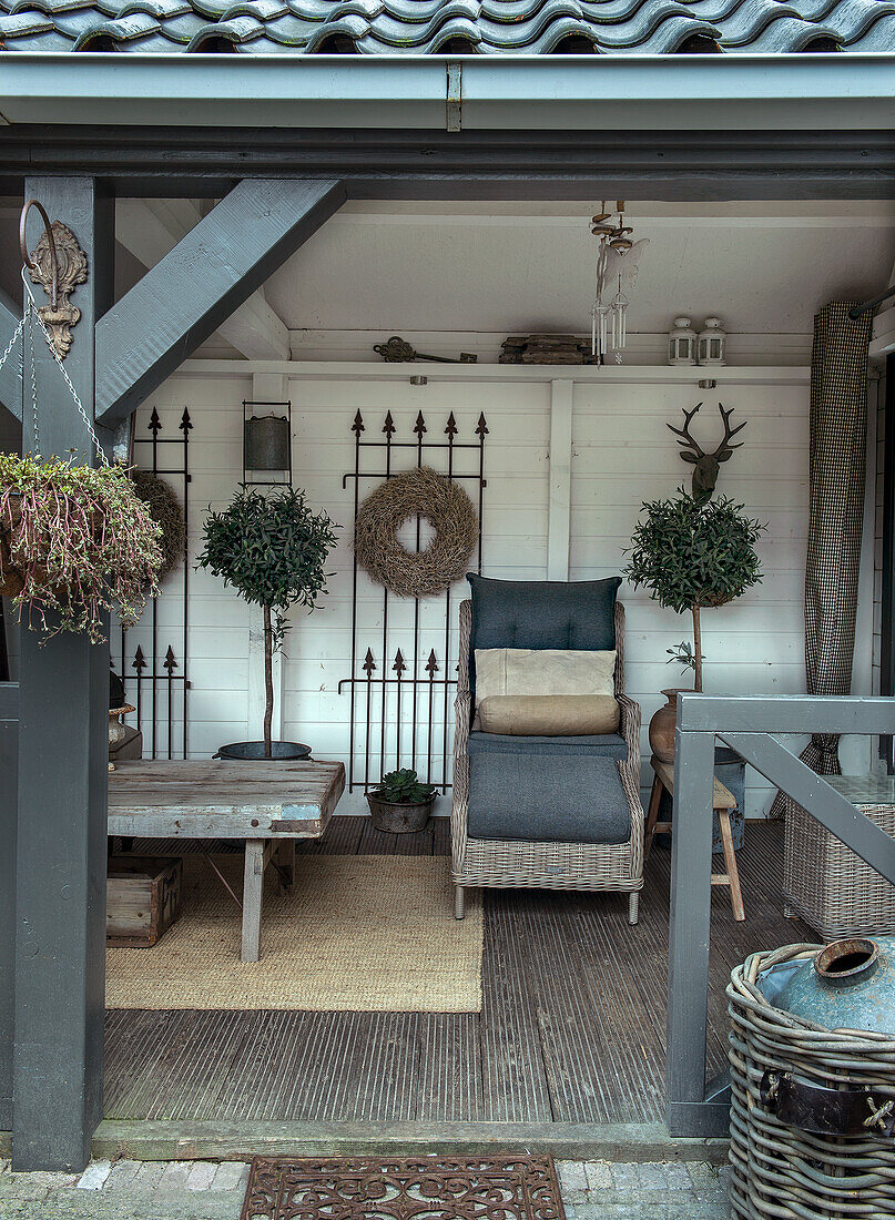 Überdachte Terrasse mit Rattan-Liegestuhl und Wanddeko