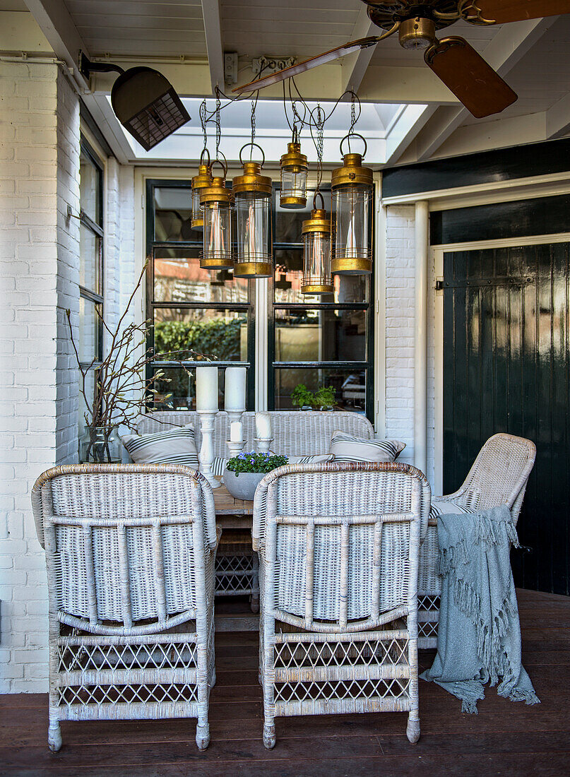 Woven rattan furniture and hanging lamps on a covered veranda