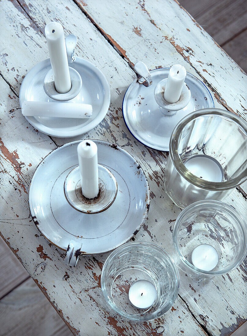 Antique white candlesticks and glass candle holders on a shabby chic wooden table