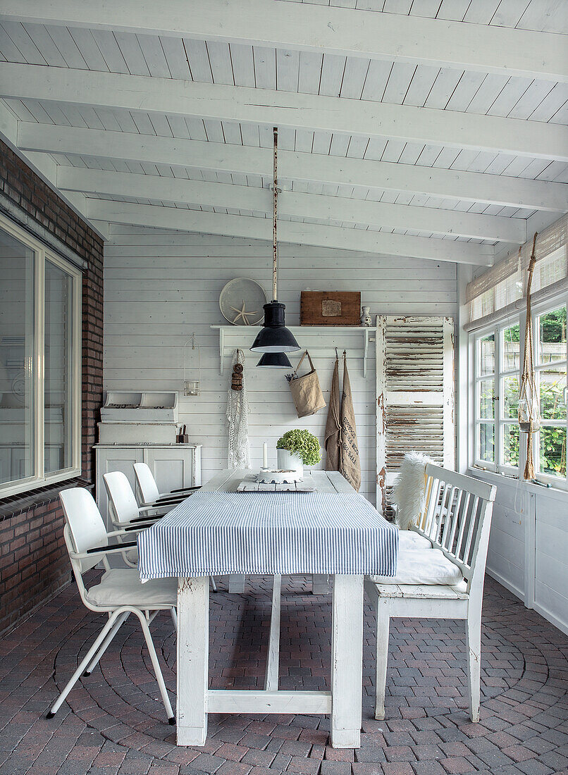 Covered veranda with white dining table and white seating