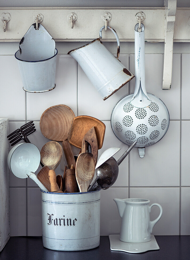 Vintage kitchen utensils and enamel crockery on hook rail