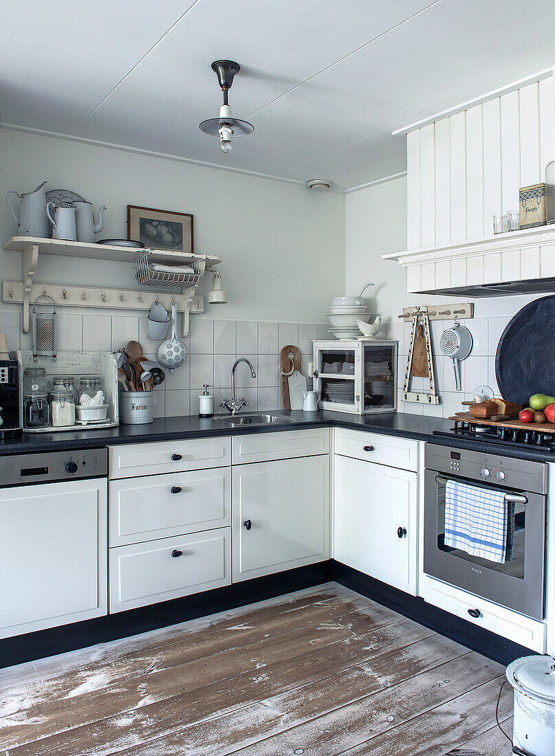 White country kitchen with black counters and wooden floor