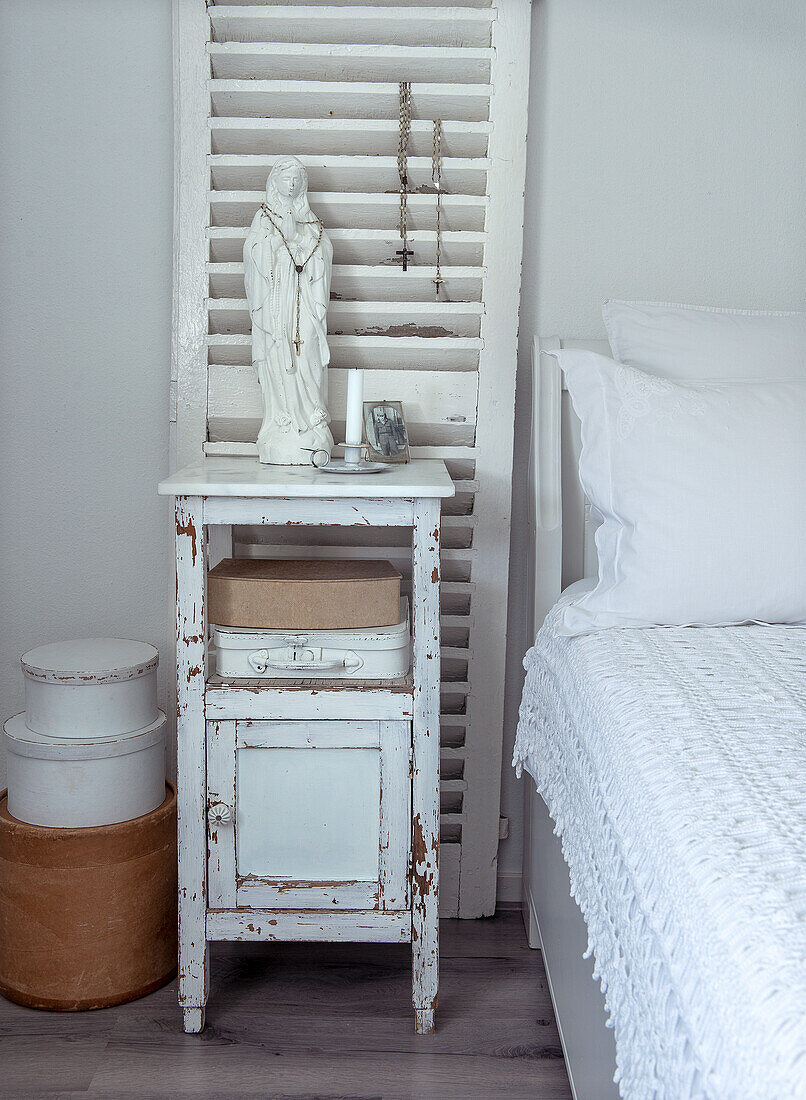 Shabby Chic-Nachttisch mit Madonnenstatue und Aufbewahrungsboxen im Schlafzimmer