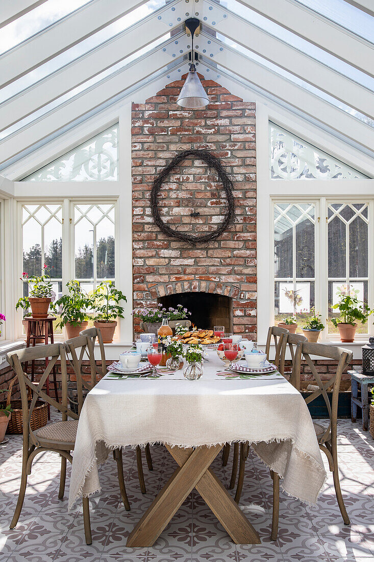 Table setting in Victorian conservatory with brick wall and plants on windowsill