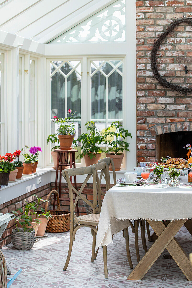 Essbereich im Wintergarten mit Ziegelwand und Pflanzen auf Fensterbank