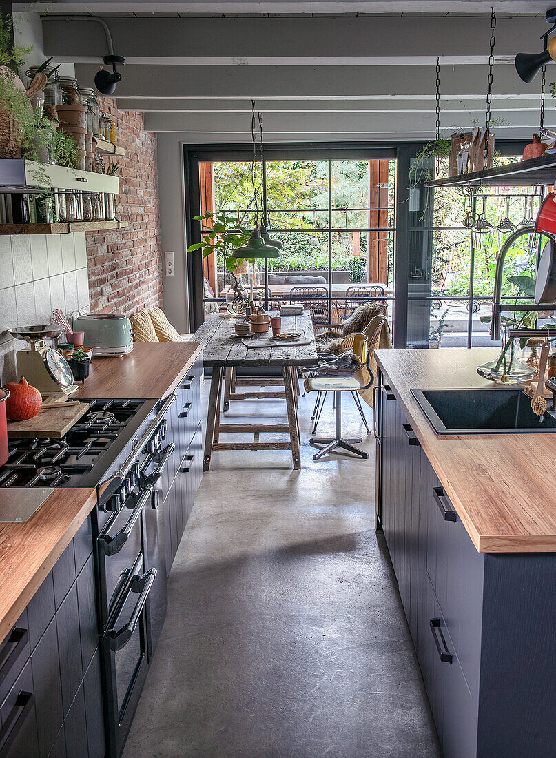 Narrow kitchen with wooden counters, black cupboards and a view of the dining area