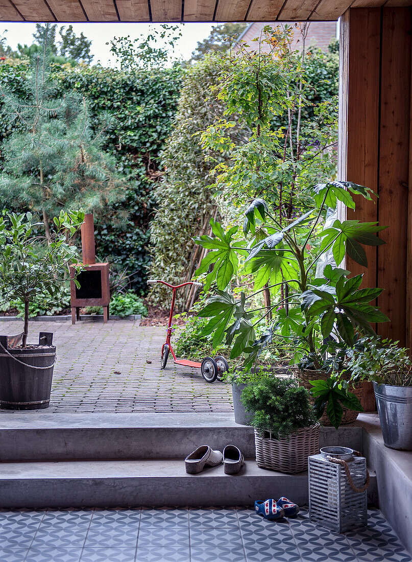 Überdachte Terrasse mit Topfpflanzen, Outdoor-Kamin und Kinderroller