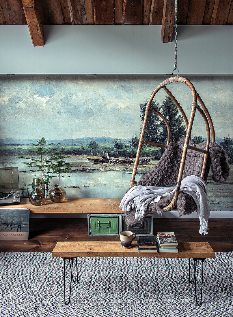 Vintage rattan hanging chair in front of a landscape mural in the living room