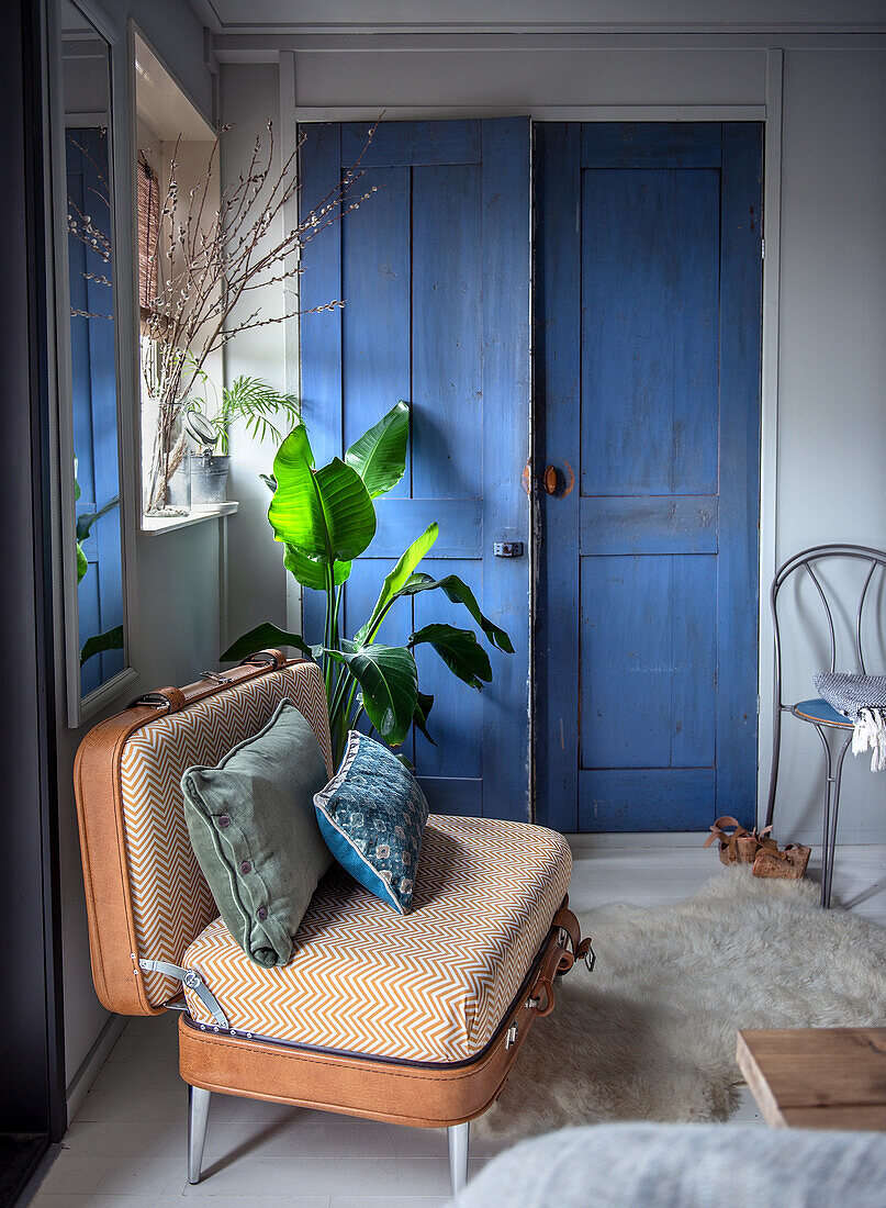 Vintage-Kofferstuhl und blaue Holztür im gemütlichen Wohnzimmer