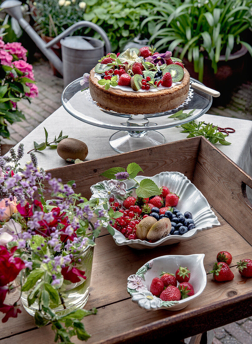 Summer cake with fresh berries and kiwi on a garden terrace