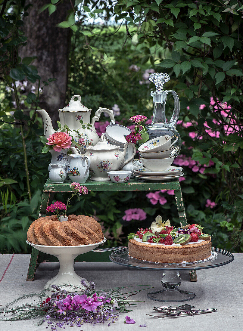 Kaffeetafel im Garten mit Porzellangeschirr, Gugelhupf und Obstkuchen