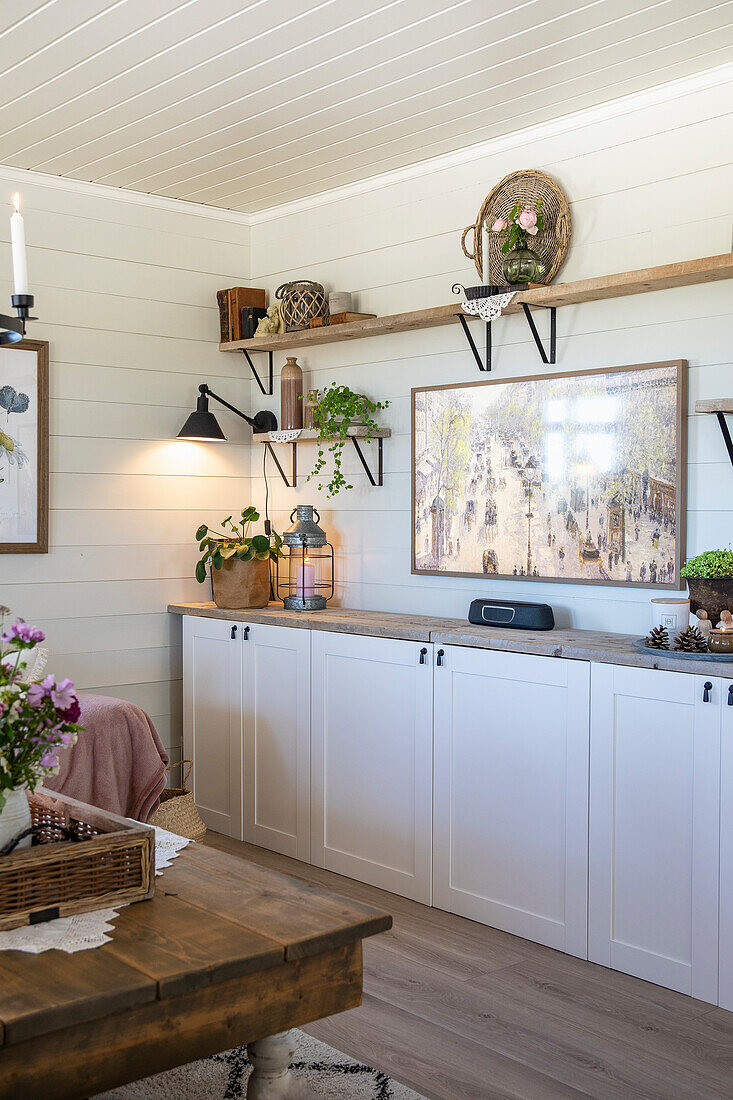 Living room corner with white built-in cupboards and rustic decoration