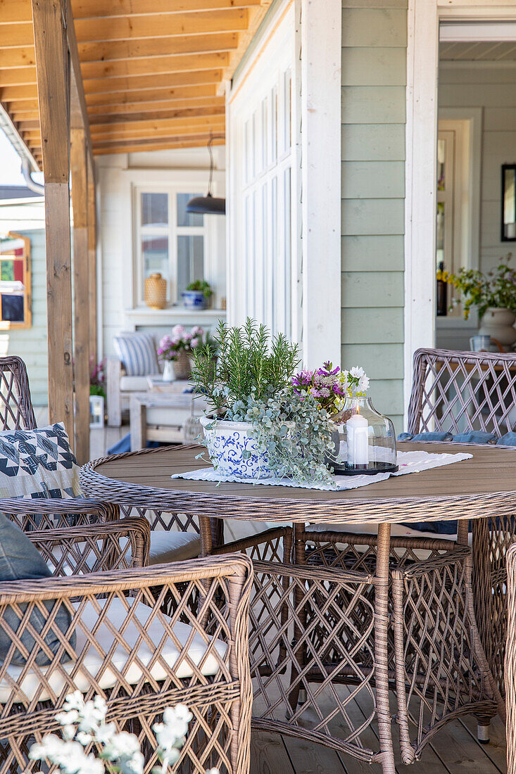 Cosy seating area on the veranda with wicker furniture and flower arrangements