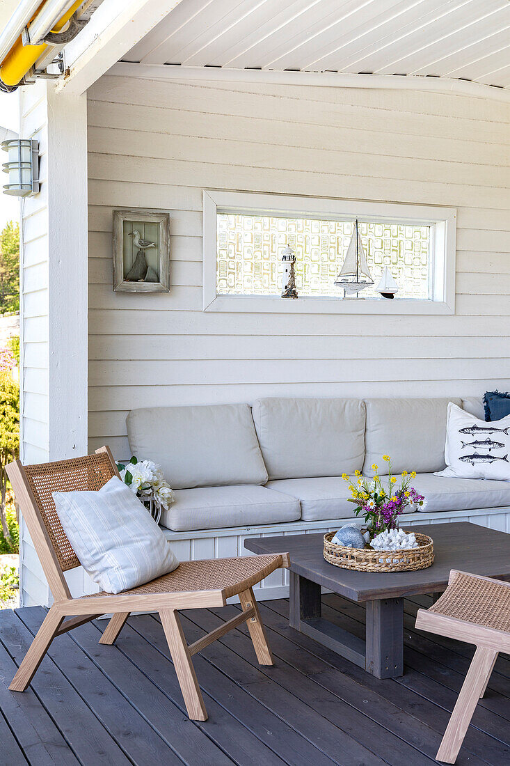 Seating area on the covered terrace with rattan furniture and maritime decorative accessories