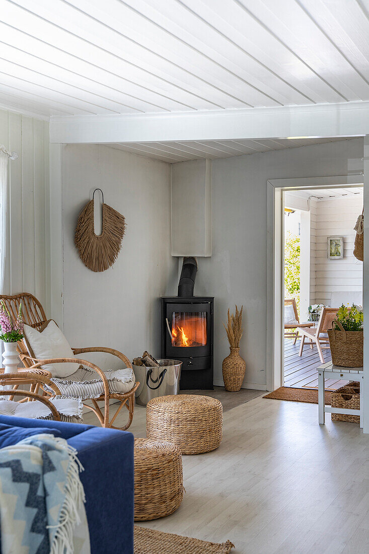 Open-plan living room with wood-burning stove and rattan furniture, adjoining veranda