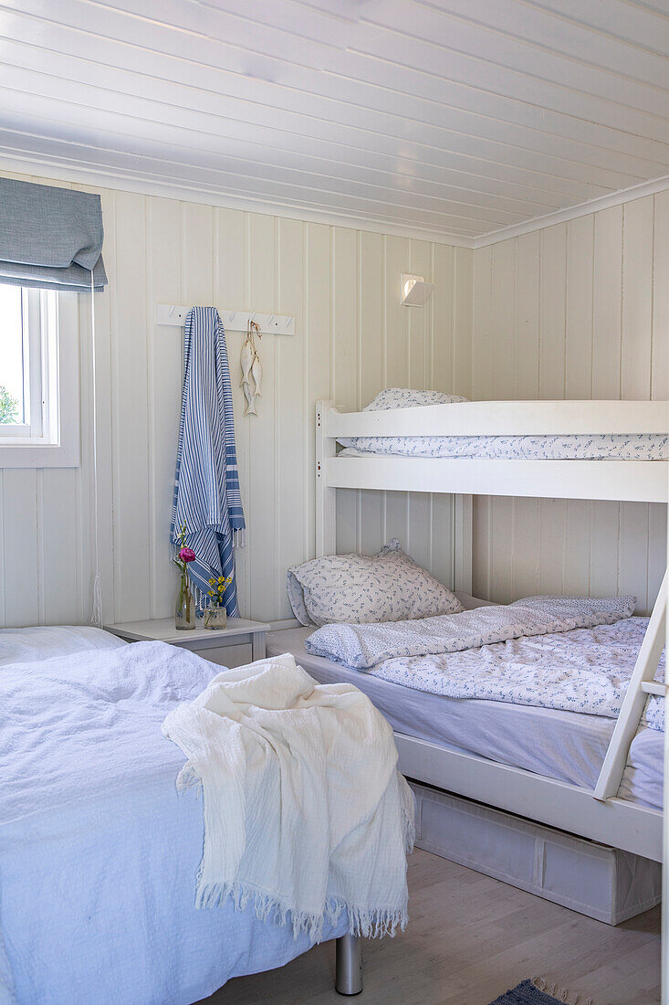 Bedroom with two beds and bunk bed and white paneled walls