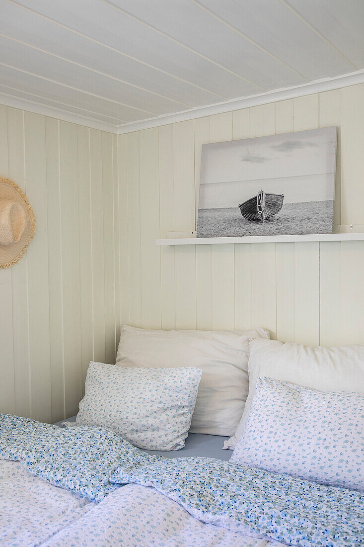 Bedroom with blue and white bed linen and light-colored wood paneling