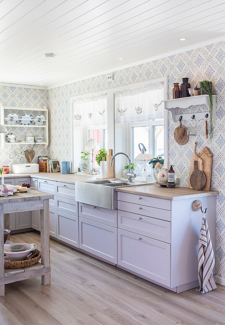 Country kitchen with white cabinets, wooden worktop and patterned wallpaper