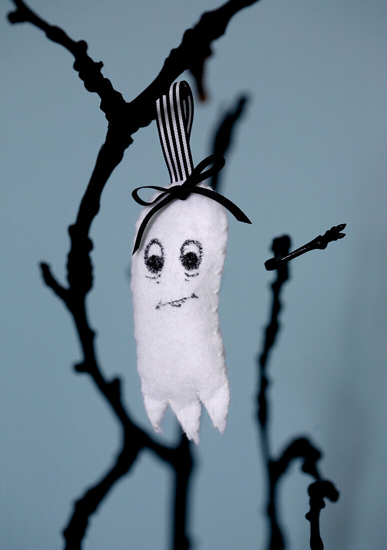 Homemade felt ghost as a Halloween decoration on a branch