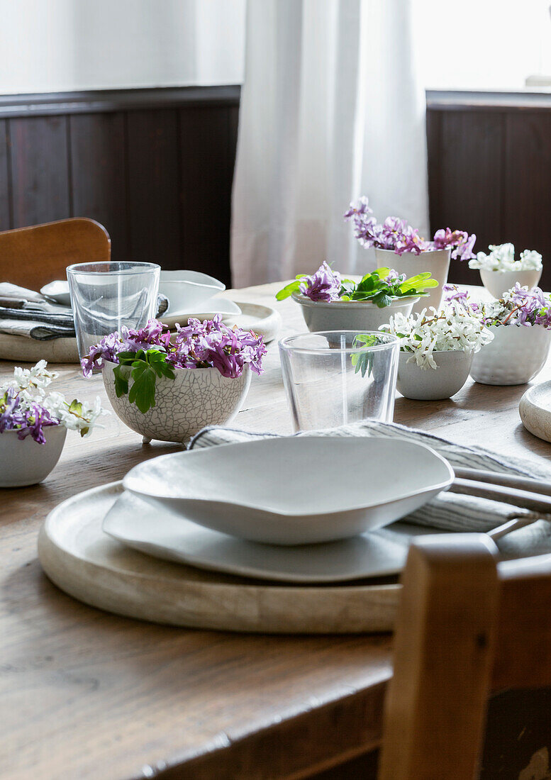 Spring dining table with white and purple flowers in ceramic bowls