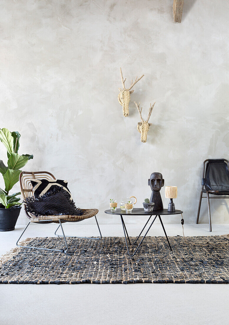 Modern seating area with rattan armchair, black accents and wall decoration made from plant fibres