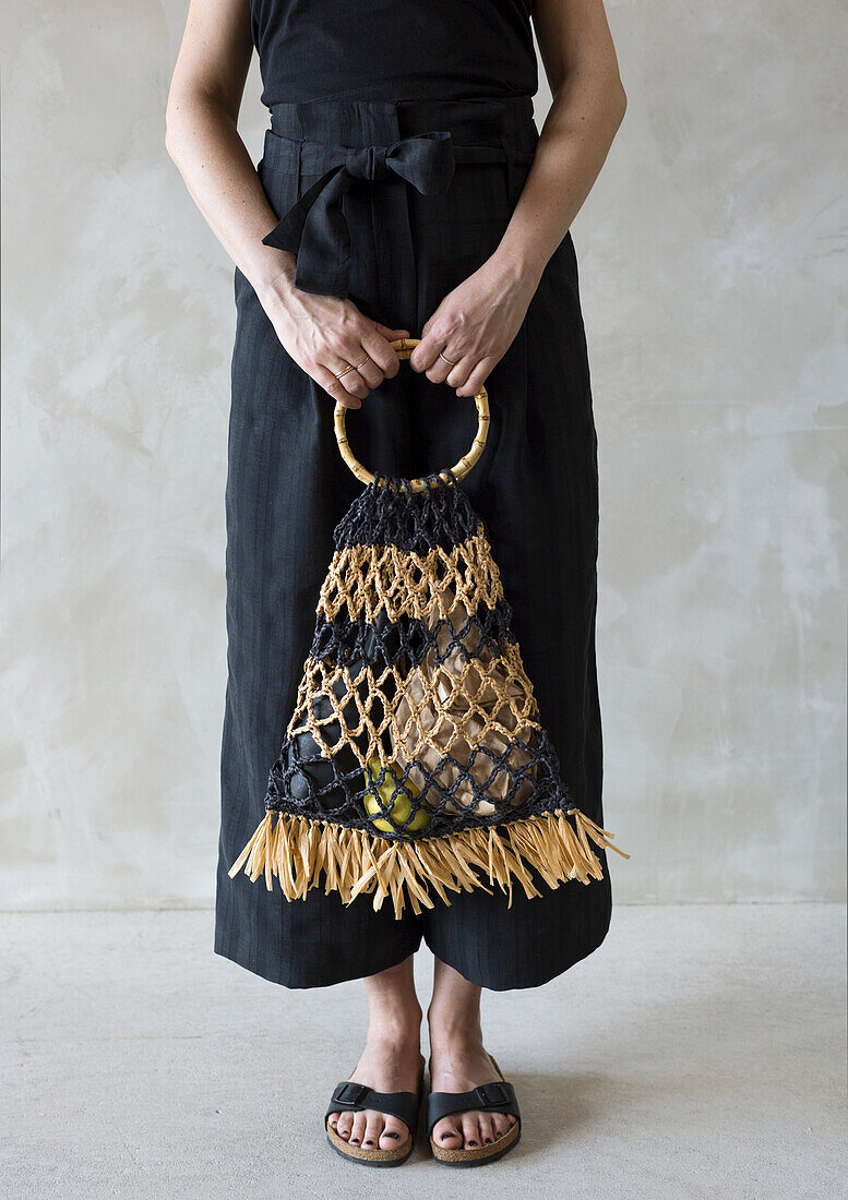 Woman with black dress and macramé bag with bamboo handle